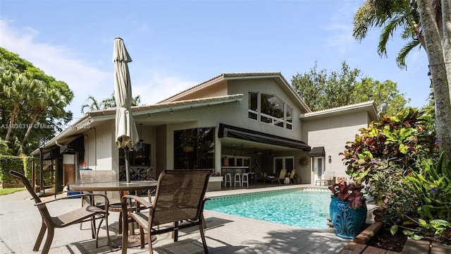 9099 NW 47th Ct, Coral Springs, FL 33067 - rear view of property featuring a patio, an outdoor pool, stucco siding, ceiling fan, and outdoor dining area
