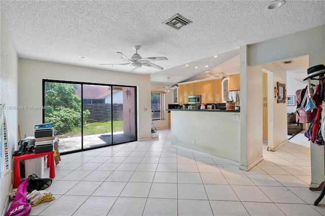 8250 NW 51st Ct, Lauderhill, FL 33351 - kitchen featuring stainless steel microwave, light brown cabinets, ceiling fan, dark countertops, and vaulted ceiling
