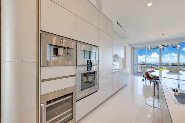 16901 Collins Ave Unit 2702, Sunny Isles Beach, FL 33160 - kitchen featuring wine cooler, a chandelier, modern cabinets, white cabinets, and light countertops