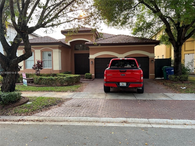 18122 NW 91st Ct, Hialeah, FL 33018 - mediterranean / spanish home with an attached garage, decorative driveway, stucco siding, and a tiled roof