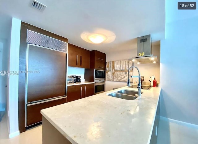 495 Brickell Ave Unit 1205, Miami, FL 33131 - kitchen with built in appliances, wall chimney exhaust hood, modern cabinets, and dark brown cabinetry
