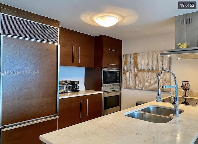 495 Brickell Ave Unit 1205, Miami, FL 33131 - kitchen with built in appliances, light countertops, dark brown cabinetry, and exhaust hood