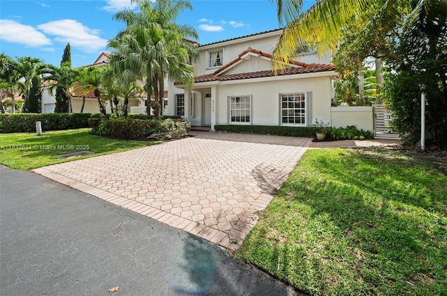 5194 NW 106th Ave, Doral, FL 33178 - mediterranean / spanish-style house featuring a front lawn, stucco siding, decorative driveway, and a tile roof