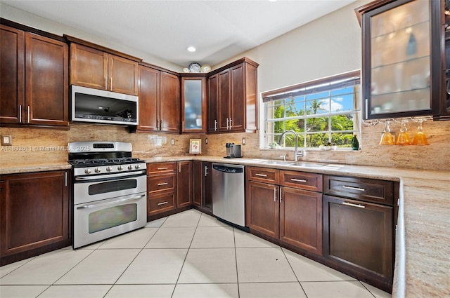 5194 NW 106th Ave, Doral, FL 33178 - kitchen featuring appliances with stainless steel finishes, light stone counters, backsplash, light tile patterned flooring, and glass insert cabinets