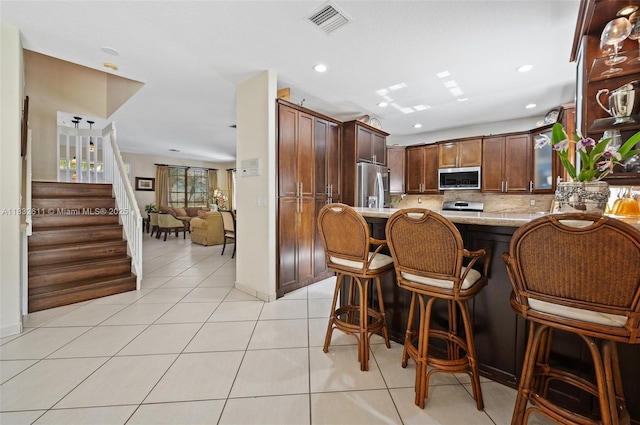 5194 NW 106th Ave, Doral, FL 33178 - kitchen with appliances with stainless steel finishes, decorative backsplash, light tile patterned floors, a kitchen breakfast bar, and a peninsula