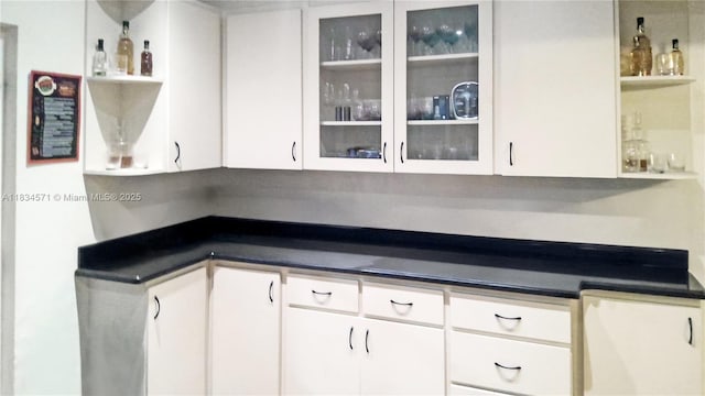 841 NE 139th St, North Miami, FL 33161 - kitchen featuring open shelves, dark countertops, white cabinets, and glass insert cabinets