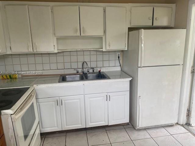 1990 NE 168th St, North Miami Beach, FL 33162 - kitchen with white appliances, light tile patterned floors, white cabinets, and decorative backsplash