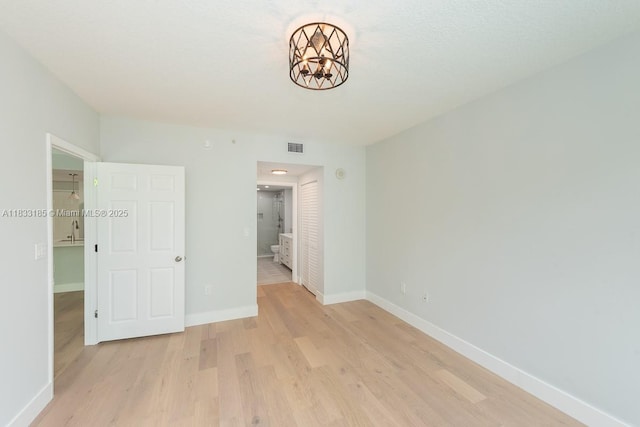 2000 N Bayshore Dr Unit 203, Miami, FL 33137 - unfurnished bedroom with a chandelier, light wood-style floors, a closet, and connected bathroom