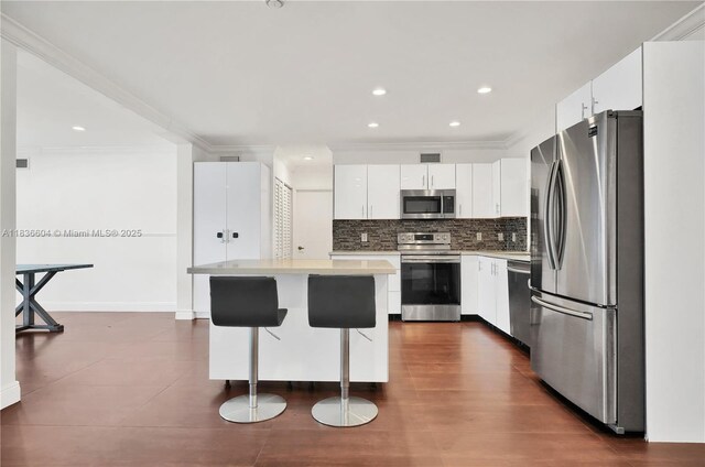 4721 W Park Rd, Hollywood, FL 33021 - kitchen with appliances with stainless steel finishes, crown molding, light countertops, decorative backsplash, and a kitchen breakfast bar