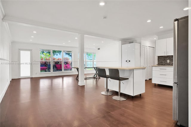 4721 W Park Rd, Hollywood, FL 33021 - kitchen featuring freestanding refrigerator, crown molding, white cabinets, a breakfast bar, and backsplash