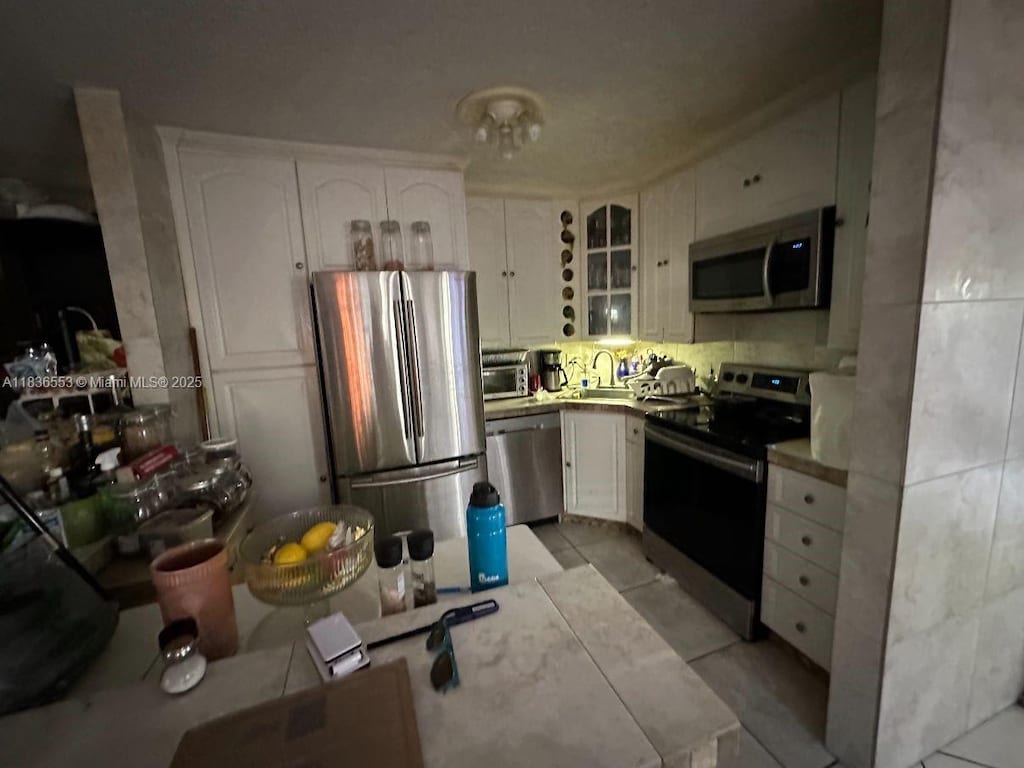 2120 SW 42nd Ter, Fort Lauderdale, FL 33317 - kitchen with stainless steel appliances, white cabinets, glass insert cabinets, and light tile patterned floors