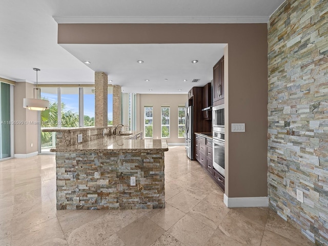 2645 S Bayshore Dr Unit 304, Miami, FL 33133 - kitchen featuring dark brown cabinetry, stainless steel appliances, stone countertops, pendant lighting, and ornamental molding