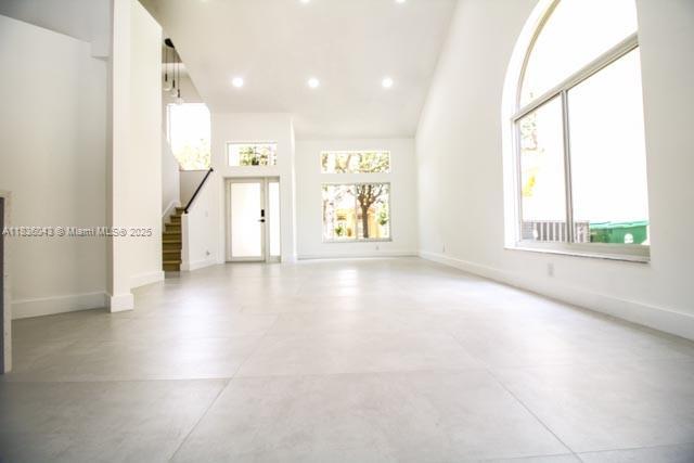 10204 Caracas St, Cooper City, FL 33026 - unfurnished living room featuring finished concrete flooring, stairs, high vaulted ceiling, and recessed lighting