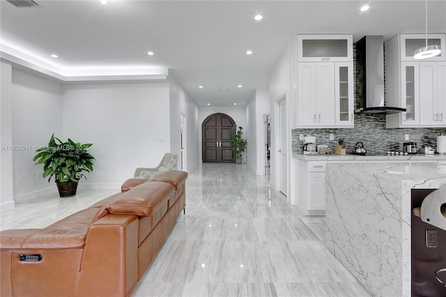 7970 SW 26th St, Miami, FL 33155 - kitchen featuring wall chimney exhaust hood, open floor plan, light stone countertops, decorative backsplash, and white cabinets