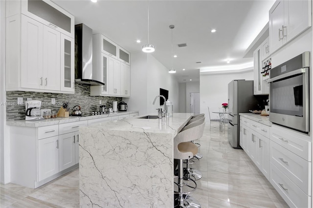 7970 SW 26th St, Miami, FL 33155 - kitchen featuring wall chimney range hood, stainless steel appliances, tasteful backsplash, a kitchen island with sink, and white cabinets