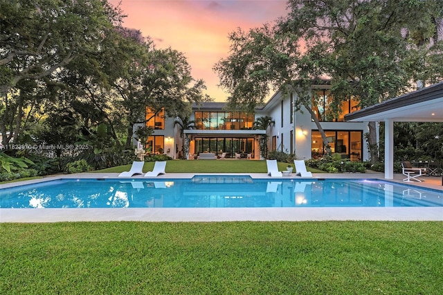 8875 SW 61st Ct, Pinecrest, FL 33156 - pool at dusk featuring an outdoor pool, a lawn, and a patio area