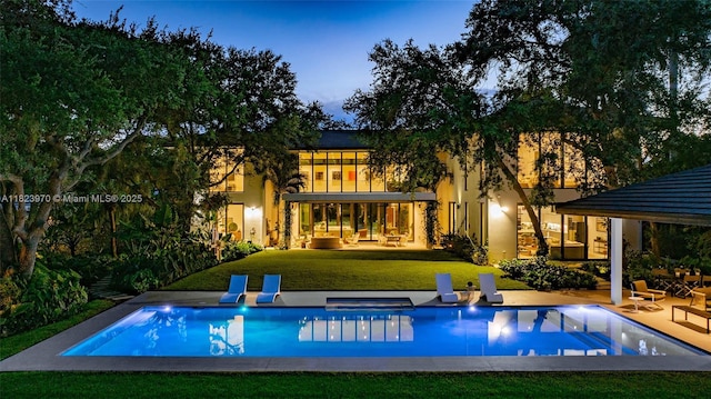 8875 SW 61st Ct, Pinecrest, FL 33156 - back of house at dusk featuring a lawn, a patio area, and a jacuzzi