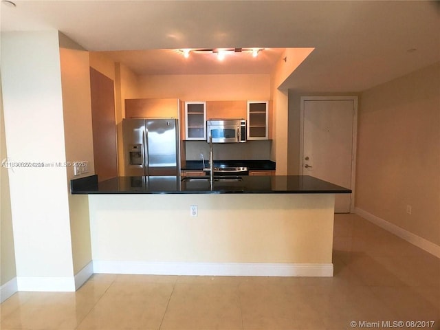 951 Brickell Ave Unit 2405, Miami, FL 33131 - kitchen with stainless steel appliances, dark countertops, a peninsula, glass insert cabinets, and light tile patterned floors