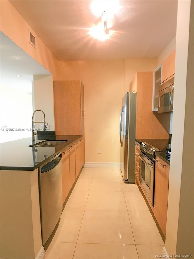 951 Brickell Ave Unit 2405, Miami, FL 33131 - kitchen with appliances with stainless steel finishes, dark countertops, light tile patterned flooring, modern cabinets, and a peninsula