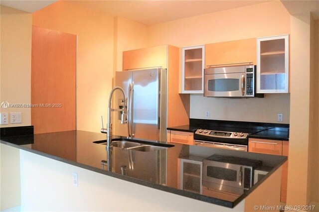 951 Brickell Ave Unit 2405, Miami, FL 33131 - kitchen featuring appliances with stainless steel finishes, glass insert cabinets, dark stone counters, and a peninsula