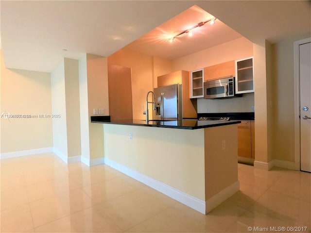 951 Brickell Ave Unit 2405, Miami, FL 33131 - kitchen with stainless steel appliances, dark countertops, light tile patterned floors, and rail lighting