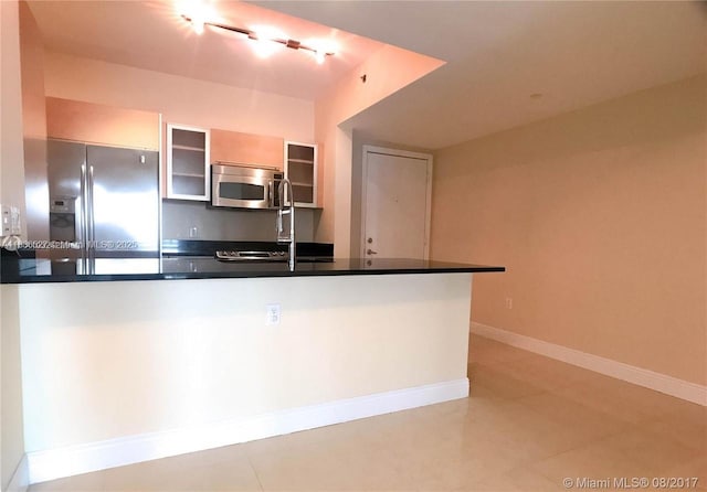 951 Brickell Ave Unit 2405, Miami, FL 33131 - kitchen featuring appliances with stainless steel finishes, dark countertops, glass insert cabinets, and light tile patterned flooring