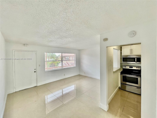 241 SE 9th Ave Unit 207, Pompano Beach, FL 33060 - kitchen featuring appliances with stainless steel finishes, a textured ceiling, light tile patterned flooring, and open floor plan