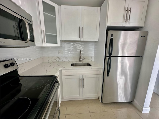 241 SE 9th Ave Unit 207, Pompano Beach, FL 33060 - kitchen with stainless steel appliances, white cabinets, light stone countertops, glass insert cabinets, and light marble finish floors