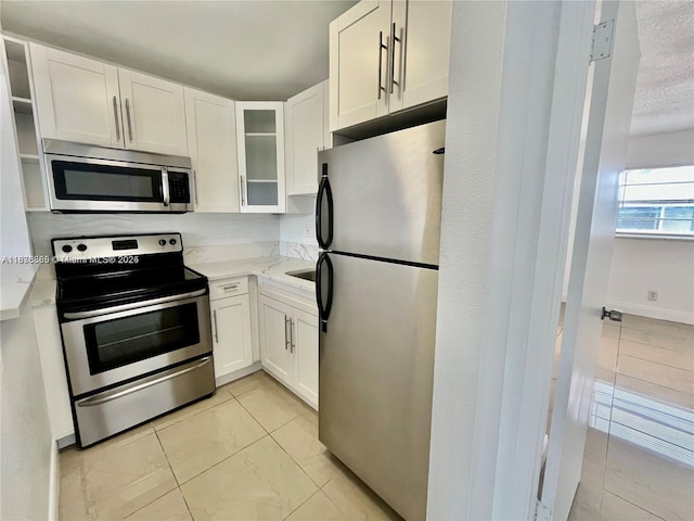 241 SE 9th Ave Unit 207, Pompano Beach, FL 33060 - kitchen with appliances with stainless steel finishes, white cabinetry, glass insert cabinets, and light stone counters