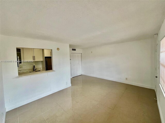 241 SE 9th Ave Unit 207, Pompano Beach, FL 33060 - spare room featuring a textured ceiling and baseboards