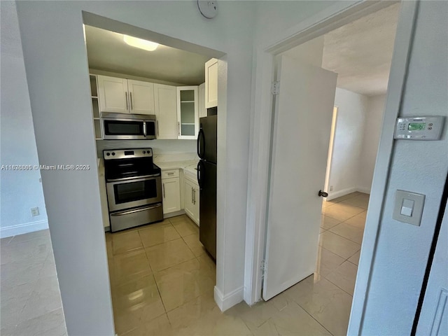 241 SE 9th Ave Unit 207, Pompano Beach, FL 33060 - kitchen with appliances with stainless steel finishes, white cabinetry, glass insert cabinets, and light countertops