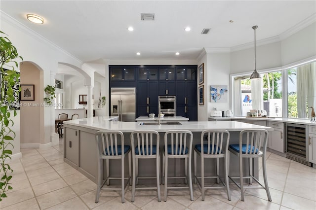 12530 SW 96th Ct, Miami, FL 33176 - kitchen with appliances with stainless steel finishes, wine cooler, light countertops, ornamental molding, and a kitchen bar
