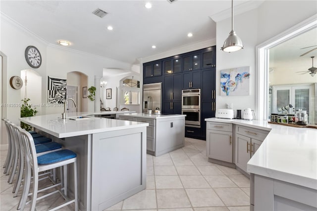 12530 SW 96th Ct, Miami, FL 33176 - kitchen featuring appliances with stainless steel finishes, a kitchen island with sink, ornamental molding, ceiling fan, and arched walkways