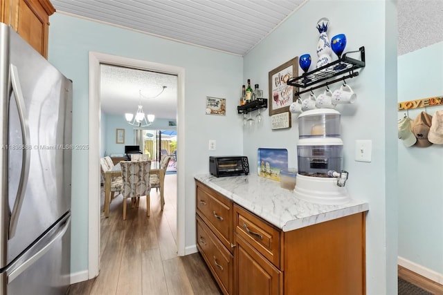 3300 Atlanta St, Hollywood, FL 33021 - kitchen with freestanding refrigerator, brown cabinetry, wood finished floors, light countertops, and a chandelier
