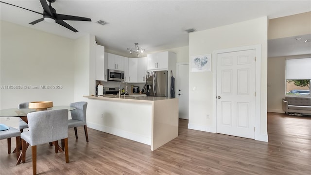 15107 NW 8th St, Pembroke Pines, FL 33028 - kitchen with stainless steel appliances, light wood-style flooring, white cabinetry, a ceiling fan, and a peninsula