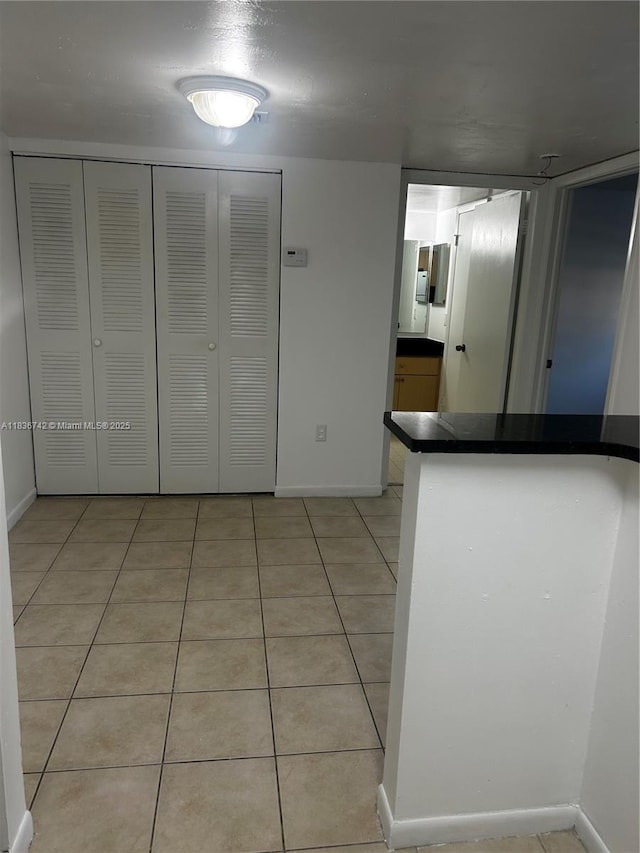 7110 NW 179th St Unit 110, Hialeah, FL 33015 - kitchen featuring dark countertops, light tile patterned flooring, and a peninsula