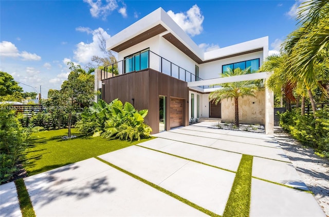1351 SW 16th St, Miami, FL 33145 - contemporary house featuring a balcony, a garage, stucco siding, and a front yard