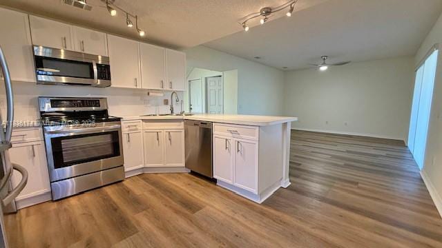 628 Turtle Run, Weston, FL 33326 - kitchen with appliances with stainless steel finishes, a peninsula, ceiling fan, white cabinets, and wood finished floors