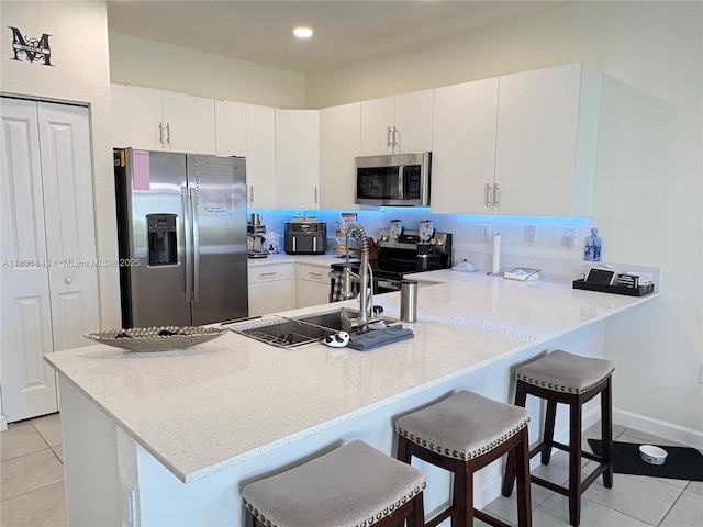3482 114th Ter, Hialeah, FL 33018 - kitchen with stainless steel appliances, light tile patterned floors, a peninsula, a breakfast bar area, and white cabinetry