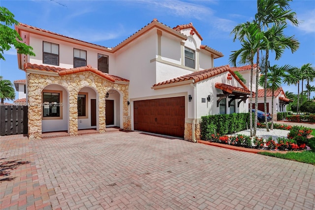 1007 NW 99th Ct, Miami, FL 33172 - mediterranean / spanish house featuring a garage, stucco siding, a tiled roof, decorative driveway, and stone siding