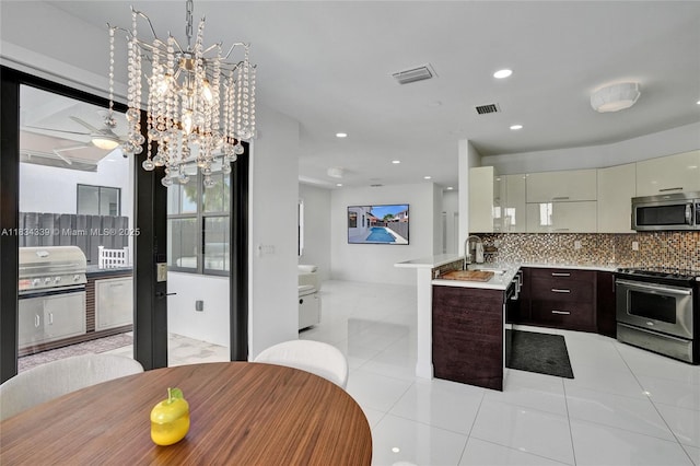 1007 NW 99th Ct, Miami, FL 33172 - kitchen with stainless steel appliances, light tile patterned floors, a chandelier, light countertops, and backsplash