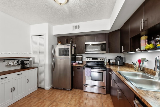 3660 N 56th Ave Unit 602, Hollywood, FL 33021 - kitchen with appliances with stainless steel finishes, dark brown cabinets, a textured ceiling, white cabinetry, and dark countertops