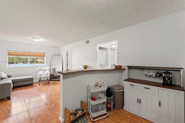3660 N 56th Ave Unit 602, Hollywood, FL 33021 - kitchen with open floor plan, a textured ceiling, light tile patterned flooring, butcher block counters, and white cabinetry
