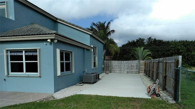 170 NE Dominican Ter, Port St Lucie, FL 34983 - view of home's exterior with a patio, stucco siding, a tiled roof, and a gate