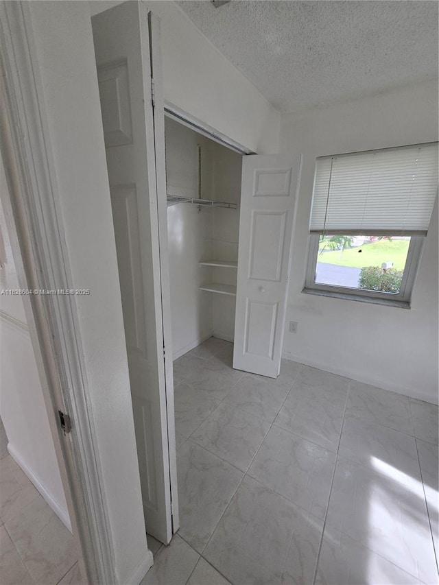 13567 SW 286th Ter, Homestead, FL 33033 - unfurnished bedroom featuring a textured ceiling, a closet, and light marble finish floors