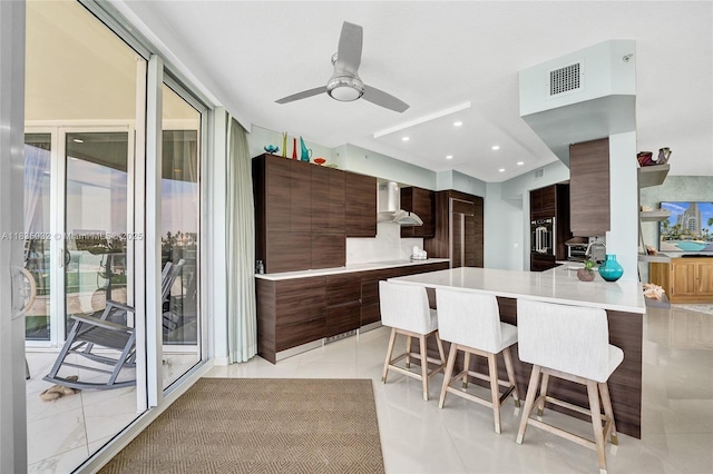 6051 N Ocean Dr Unit 404, Hollywood, FL 33019 - kitchen with modern cabinets, wall chimney range hood, a breakfast bar area, light countertops, and recessed lighting