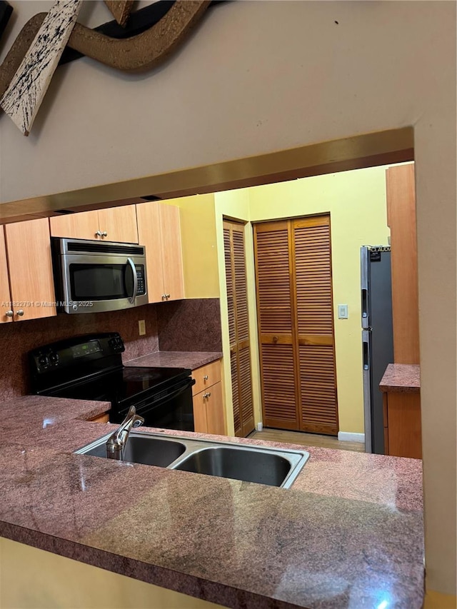 11248 SW 11th St, Pembroke Pines, FL 33025 - kitchen featuring stainless steel microwave, black range with electric cooktop, freestanding refrigerator, light brown cabinets, and decorative backsplash