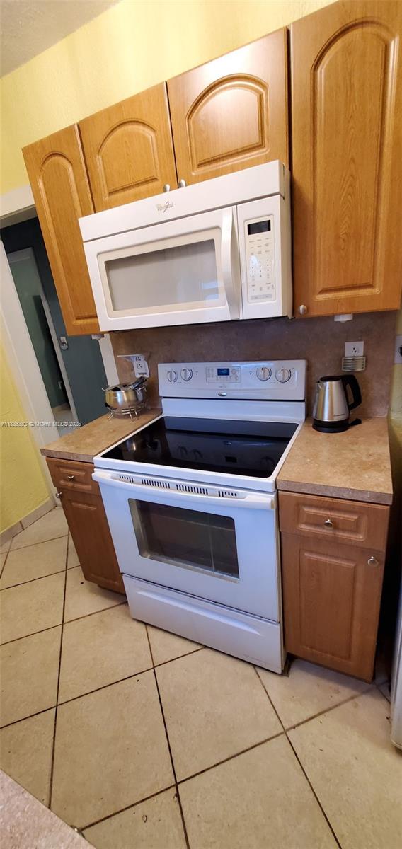 1679 NE 175th St, North Miami Beach, FL 33162 - kitchen with white appliances, light tile patterned floors, and light countertops