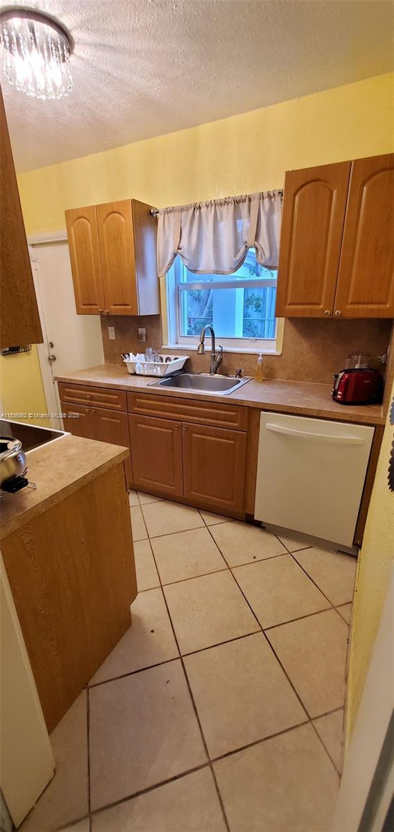 1679 NE 175th St, North Miami Beach, FL 33162 - kitchen with white dishwasher, a textured ceiling, light tile patterned floors, and light countertops