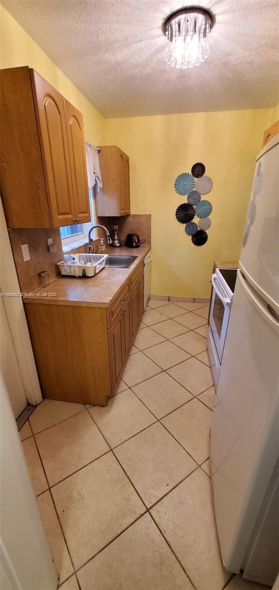 1679 NE 175th St, North Miami Beach, FL 33162 - kitchen with white appliances, a textured ceiling, light tile patterned flooring, and light countertops
